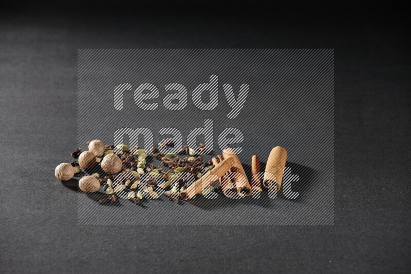 Cardamom, cloves, nutmeg and cinnamon sticks on black flooring