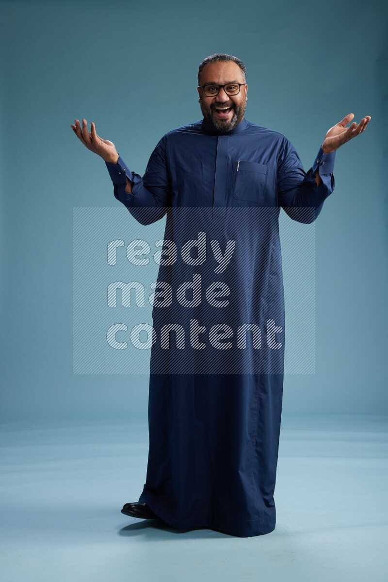 Saudi Man without shimag Standing Interacting with the camera on blue background