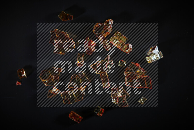 Transparent orange fragments of glass scattered on a black background