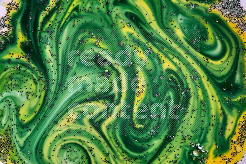 A close-up of sparkling green glitter scattered on swirling yellow and green background