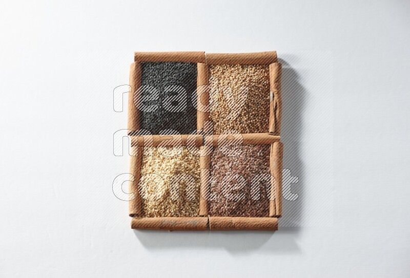 4 squares of cinnamon sticks full of black seeds, mustard seeds, flaxseeds and sesame on white flooring