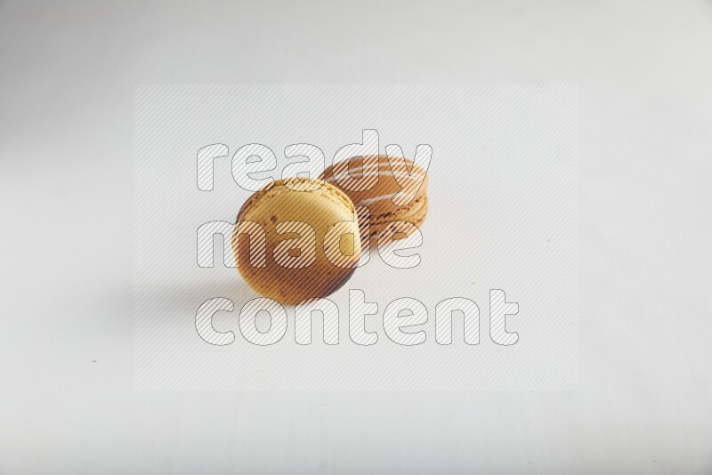 45º Shot of of two assorted Brown Irish Cream, and Yellow Crème Brulée macarons on white background