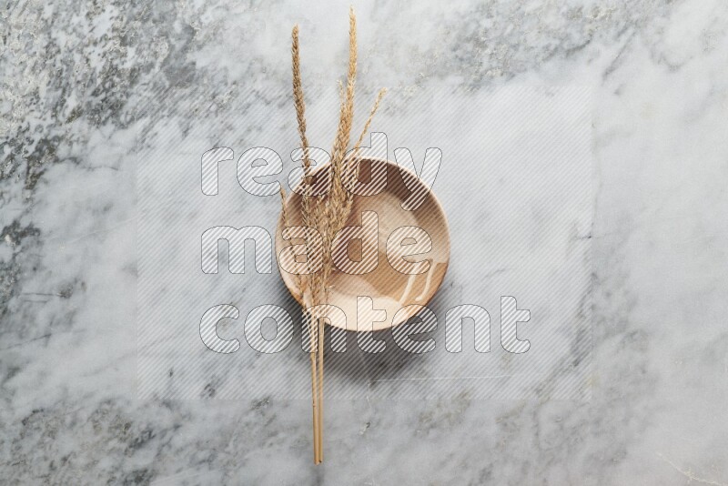 Wheat stalks on multicolored pottery plate on grey marble background