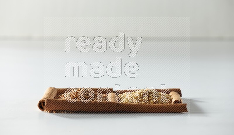 2 squares of cinnamon sticks full of mustard seeds and sesame on white flooring