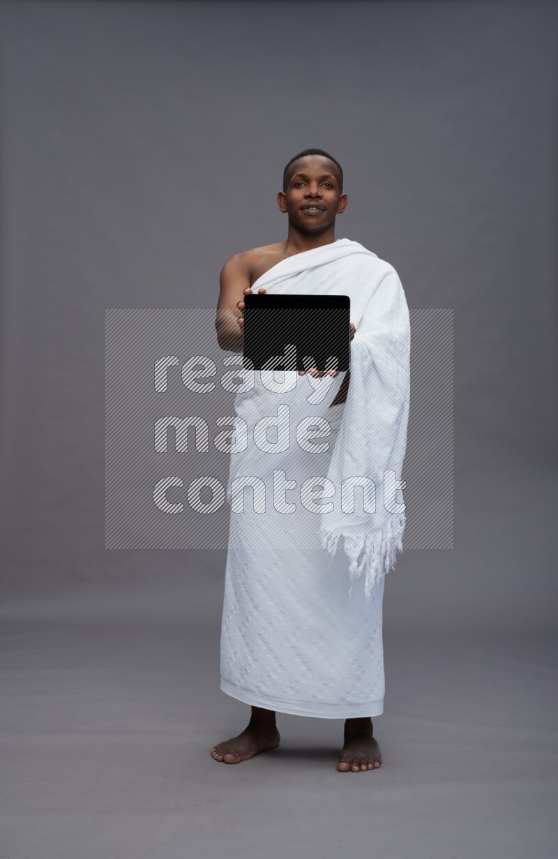 A man wearing Ehram Standing showing tablet to camera on gray background