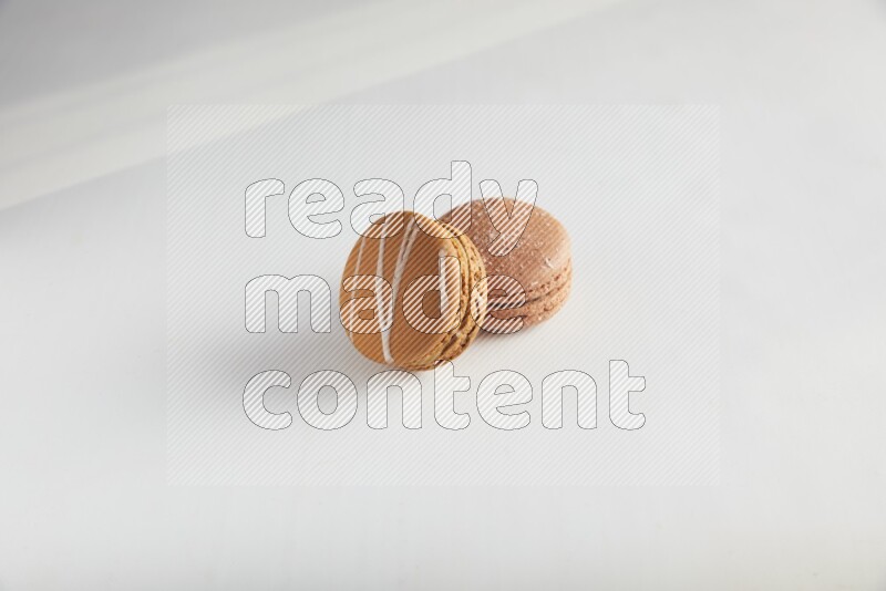 45º Shot of of two assorted Brown Irish Cream, and Brown Hazelnuts macarons on white background