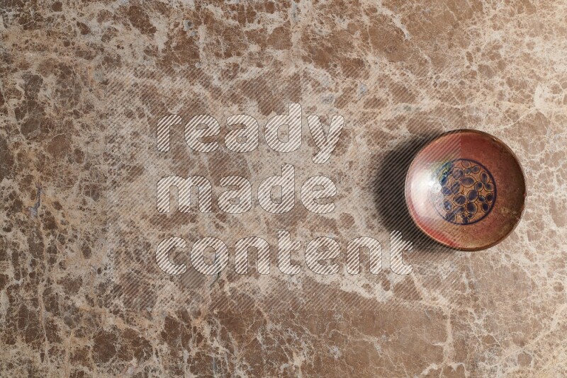 A decorative pottery plate on beige marble background