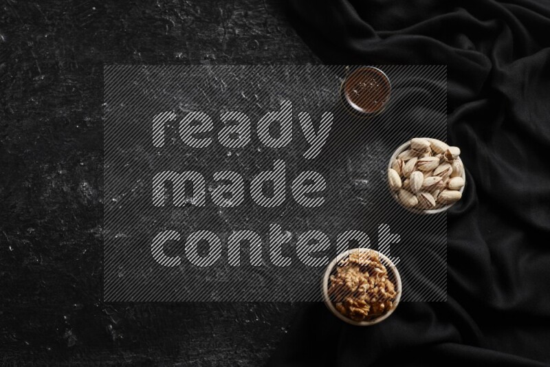 Nuts in pottery bowls with coffee in a dark setup