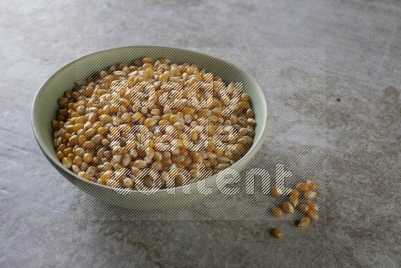 corn kernel in a green ceramic bowl on a grey textured countertop