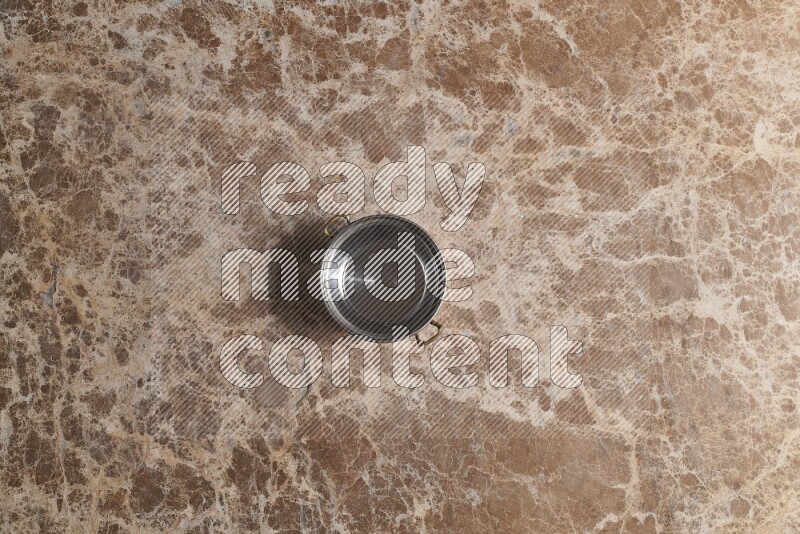 A small copper pot on beige marble background