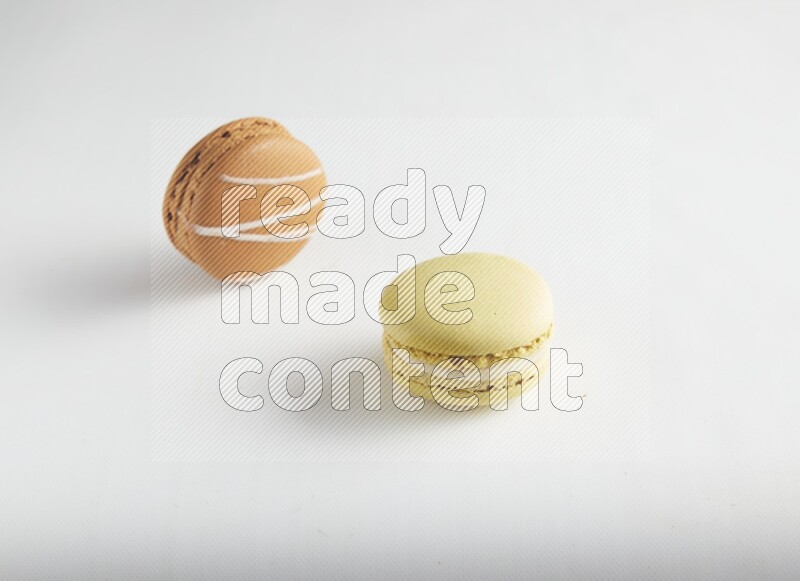 45º Shot of of two assorted Brown Irish Cream, and Yellow Lime macarons on white background