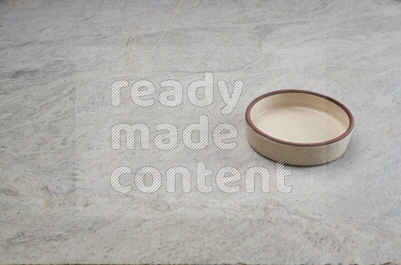 A beige pottery oven bowl on grey marble background