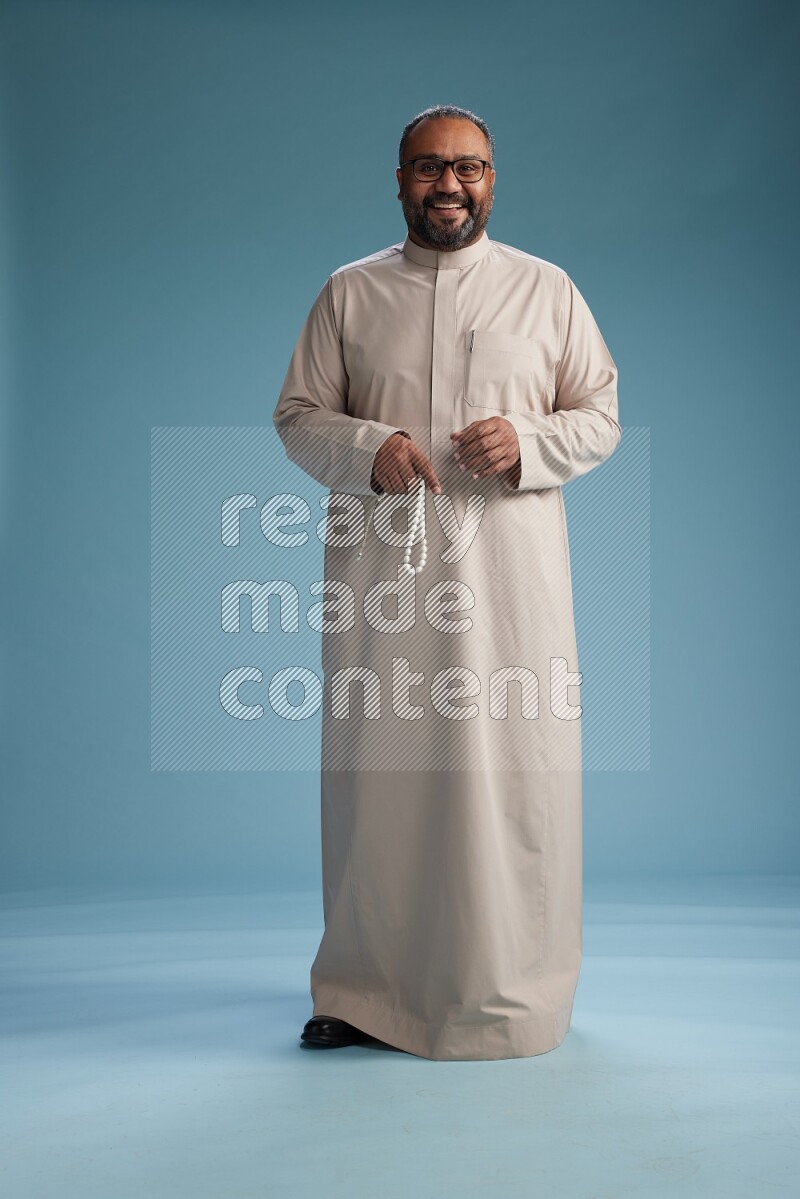 Saudi Man without shimag Standing Interacting with the camera on blue background