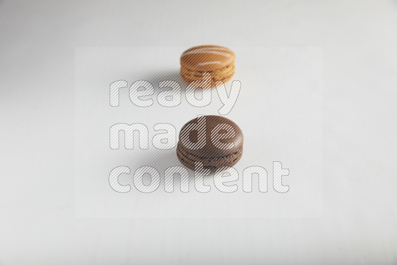 45º Shot of of two assorted Brown Irish Cream, and Brown Dark Chocolate macarons on white background