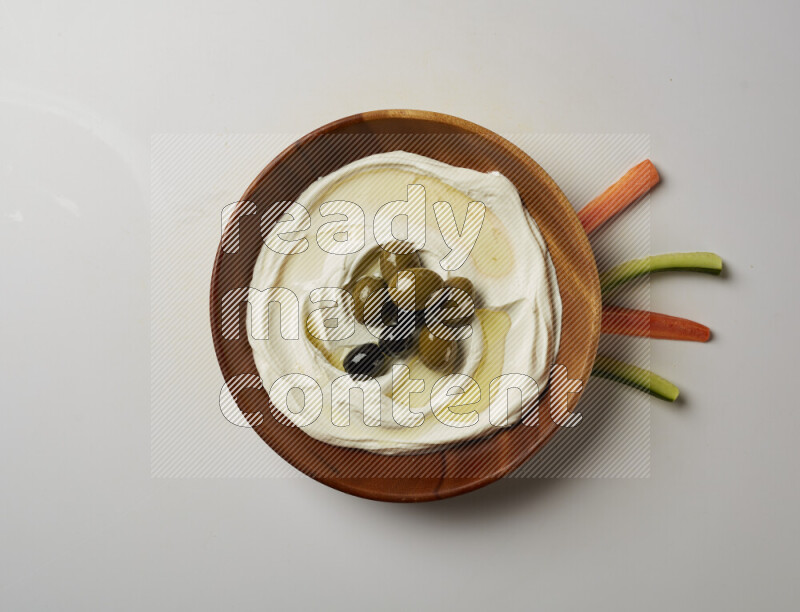 Lebnah garnished with whole olives in a wooden plate on a white background