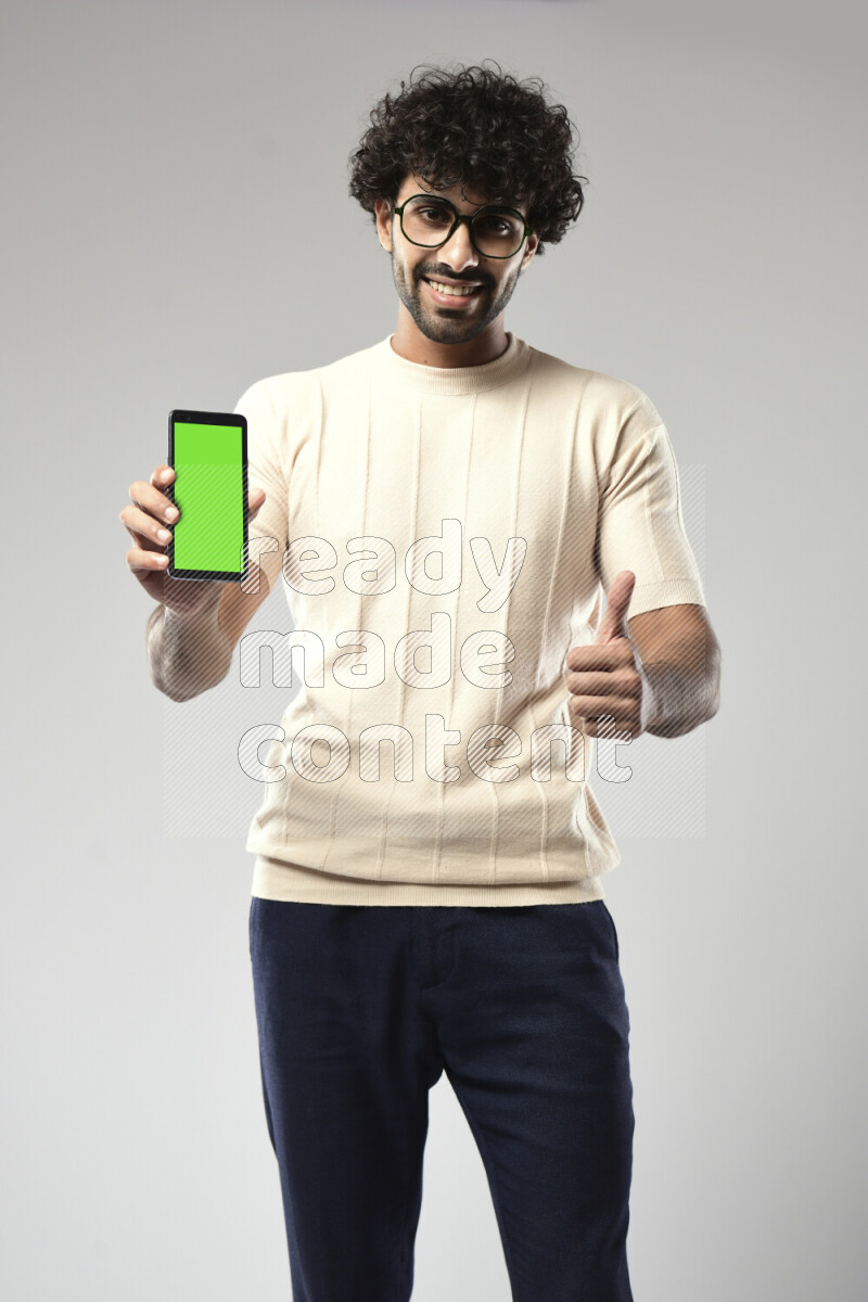 A man wearing casual standing and showing a phone screen on white background