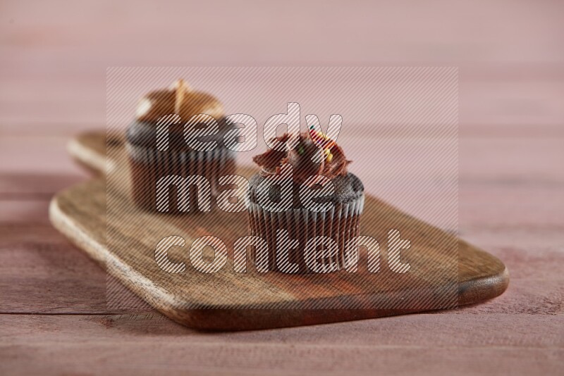 Chocolate mini cupcake topped with chocolate cream on a wooden board