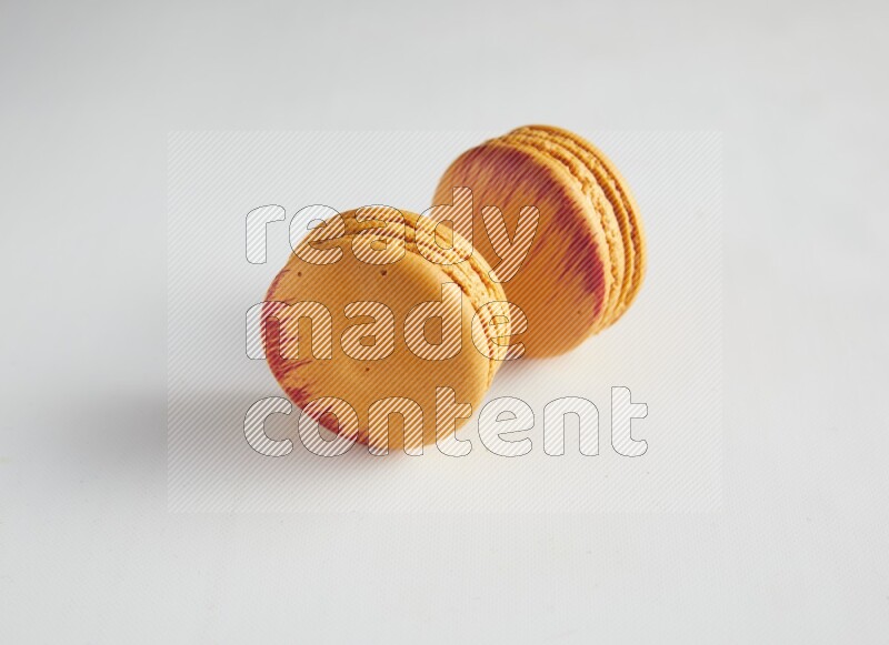 45º Shot of two orange Exotic macarons on white background