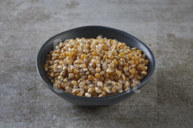 corn kernel in a black ceramic bowl on a grey textured countertop