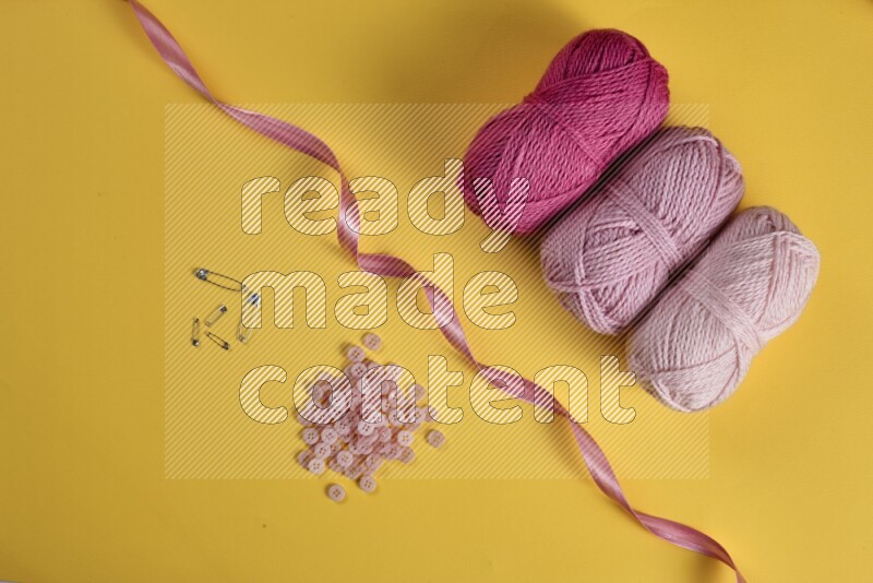 A pink collection of sewing and tailoring tools arranged on a yellow background