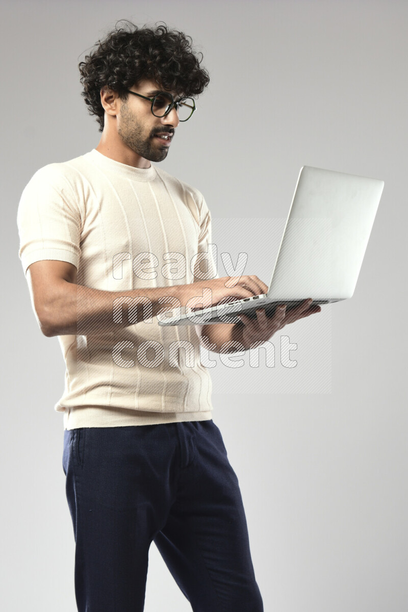 A man wearing casual standing and working on a laptop on white background