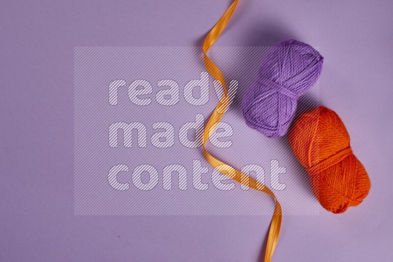 مجموعة من أدوات الخياطة والتفصيل برتقالية اللون على خلفية أرجوانية