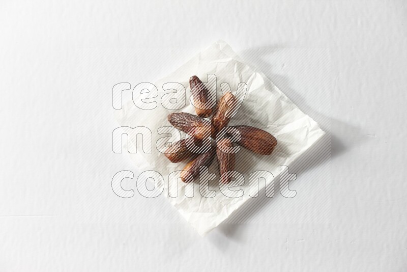 Dried dates on a crumpled piece of paper on a white background in different angles