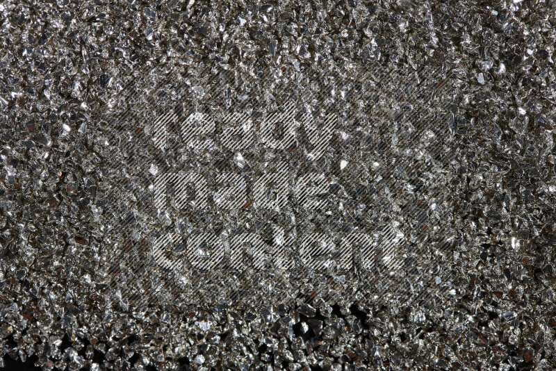 Silver shimmering fragments of glass scattered on a black background