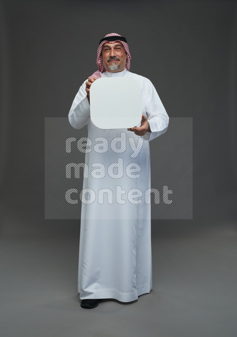 Saudi man with shomag Standing holding social media sing on gray background