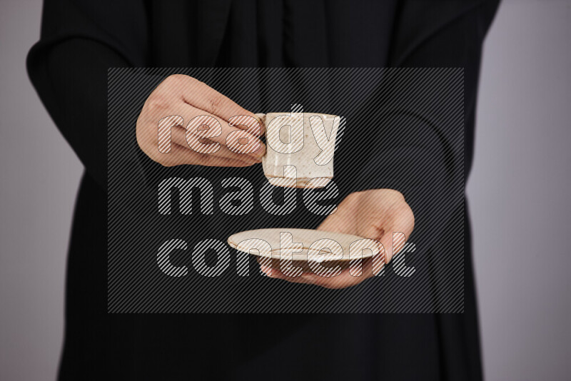 A woman in black abaya holding different pottery essentials in different positions
