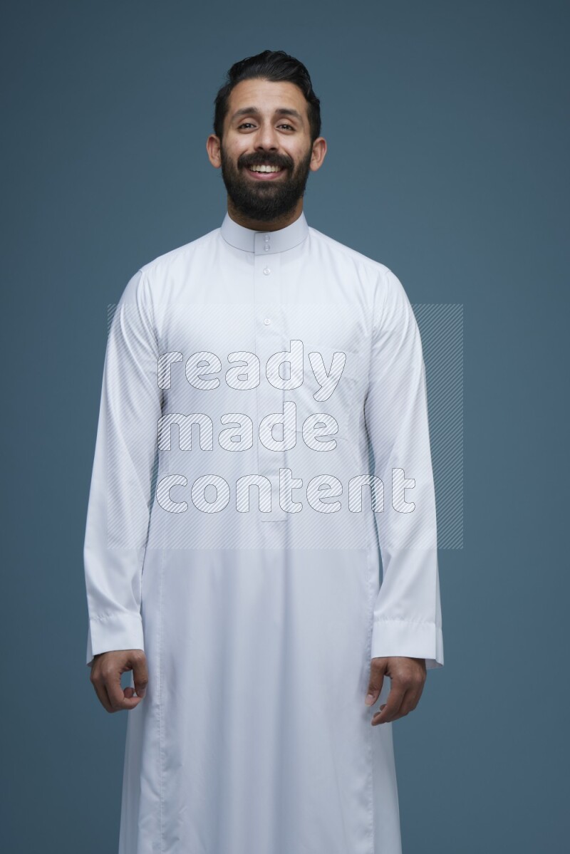 A man posing in a blue background wearing Saudi Thob