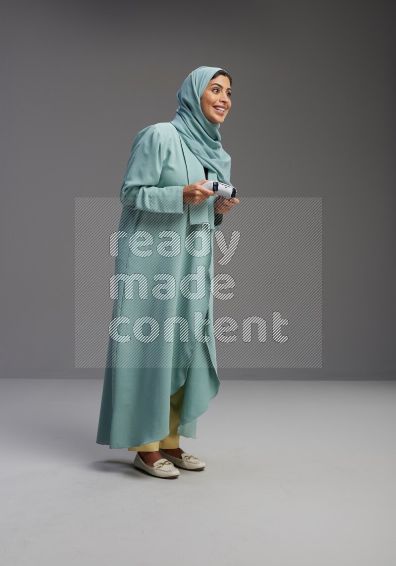 Saudi Woman wearing Abaya standing Playing Games on Gray background