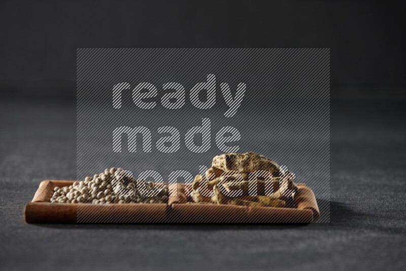 2 squares of cinnamon sticks full of white pepper and turmeric fingers on black flooring