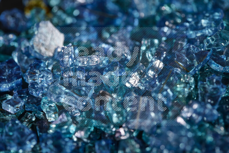 Transparent blue fragments of glass scattered on a black background