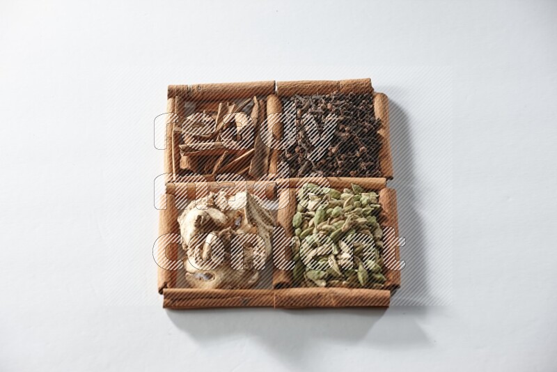 4 squares of cinnamon sticks full of cardamom, cinnamon, cloves and dried ginger on white flooring