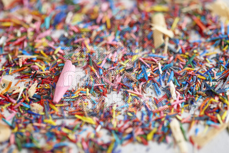 This image showcases a vibrant multicolored pencil shavings scattered on grey background