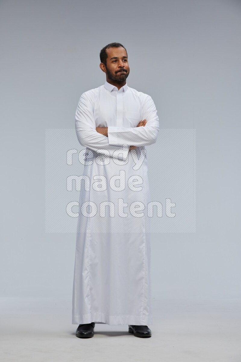 Saudi man wearing Thob standing with crossed arms on Gray background