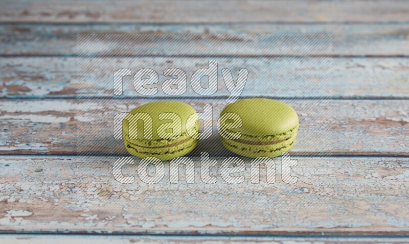 45º Shot of two Green Pistachio macarons on light blue wooden background