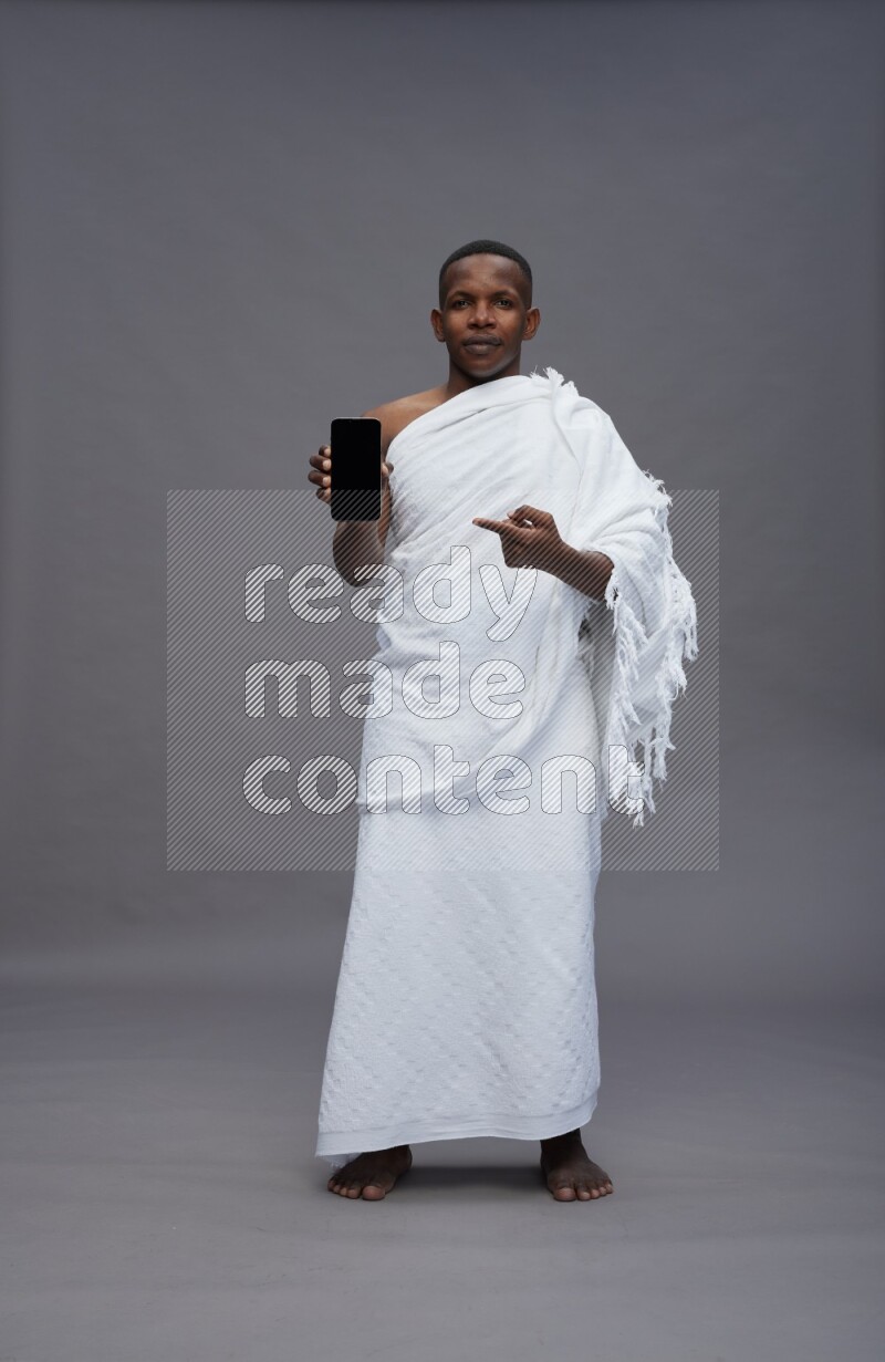 A man wearing Ehram Standing showing phone to camera on gray background