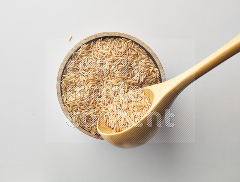 Top-view shot of long grain brown rice in a container on white background