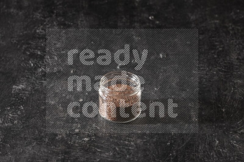 وعاء زجاجي ممتلئ بحبوب بذر الكتان علي خلفية سوداء