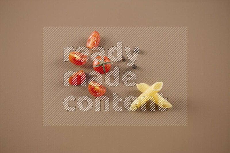 Raw pasta with different ingredients such as cherry tomatoes, garlic, onions, red chilis, black pepper, white pepper, bay laurel leaves, rosemary and cardamom on beige background