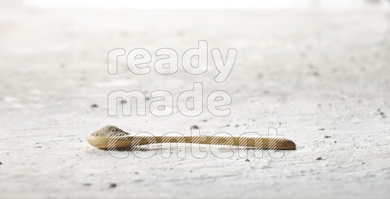 A wooden spoon full of white pepper powder on textured white flooring