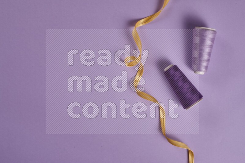 A yellow and purple collection of sewing and tailoring tools arranged on a purple background