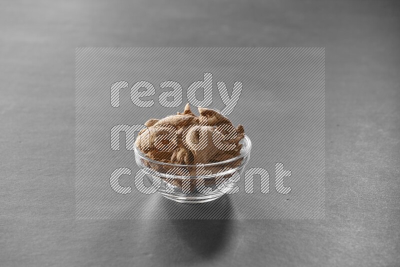 A glass bowl full of ginger on black flooring