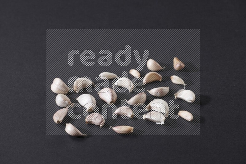 Scattered garlic cloves on a black flooring