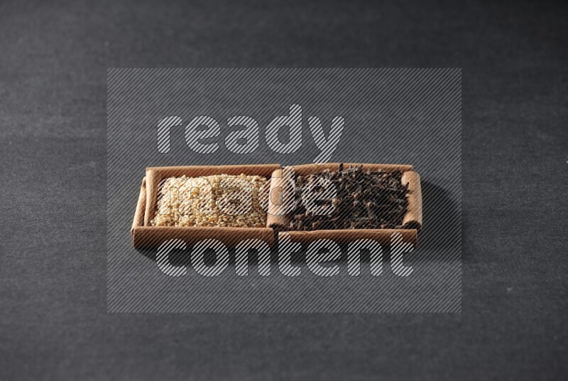2 squares of cinnamon sticks full of sesame and cloves on black flooring