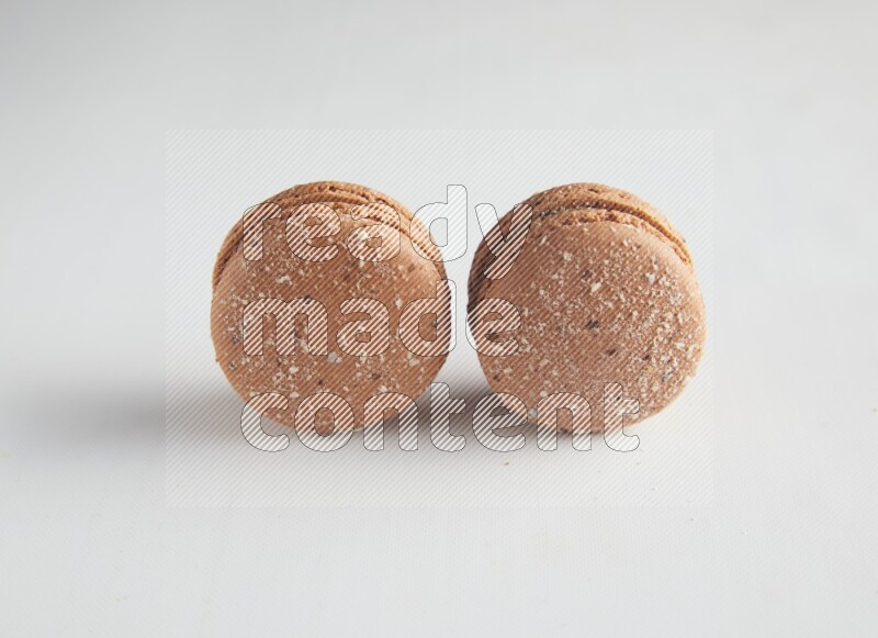 45º Shot of two Brown Hazelnuts macarons on white background