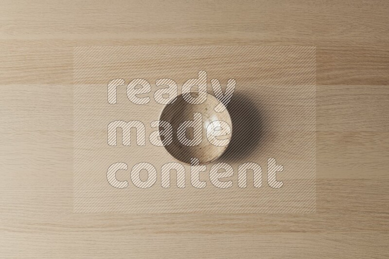 A multicolored pottery bowl on light wooden background
