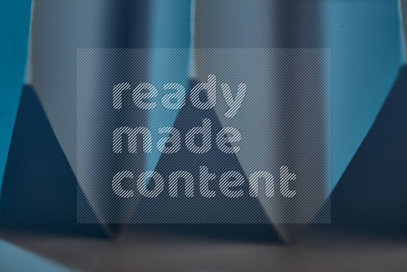 A close-up abstract image showing sharp geometric paper folds in blue gradients